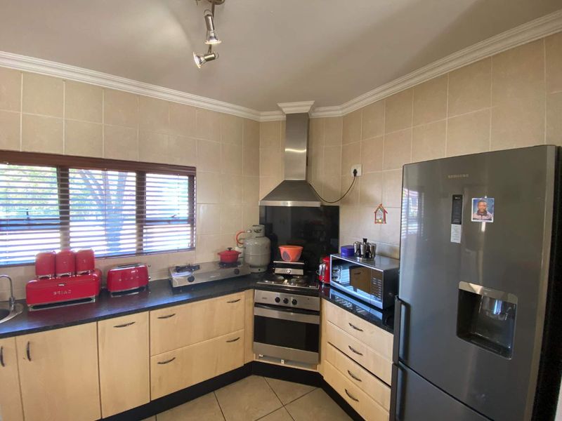 A functional kitchen featuring light wood cabinetry, dark countertops, a stainless steel oven with gas hob, and a tiled backsplash.