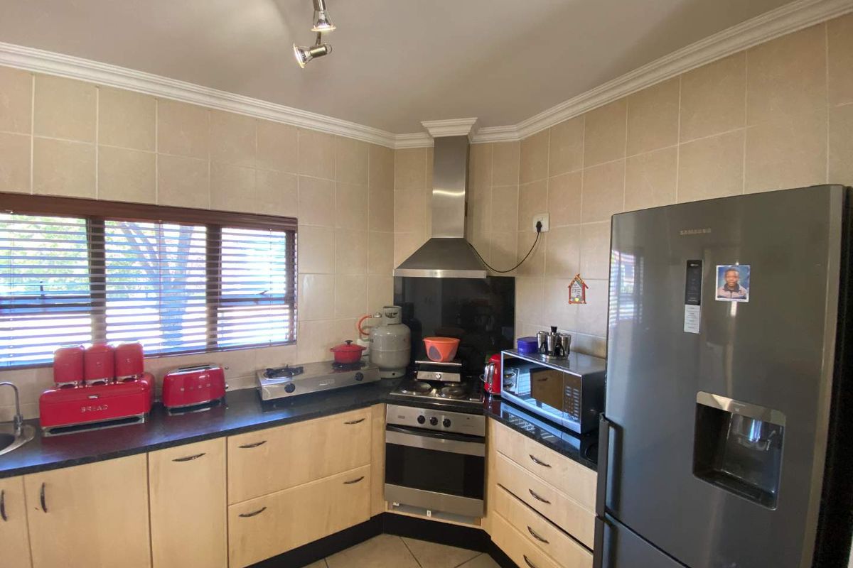 A functional kitchen featuring light wood cabinetry, dark countertops, a stainless steel oven with gas hob, and a tiled backsplash.