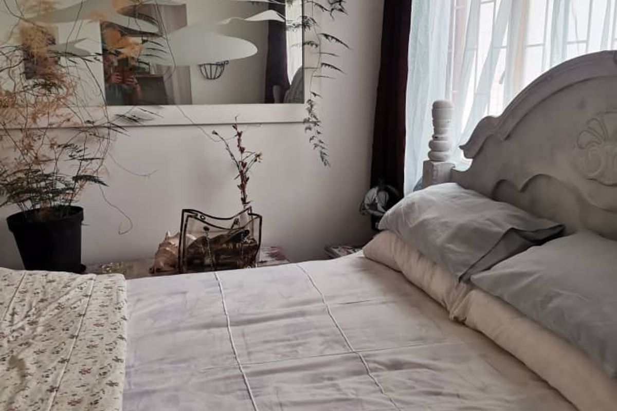 A bedroom featuring a window with security bars and a wall-mounted mirror.
