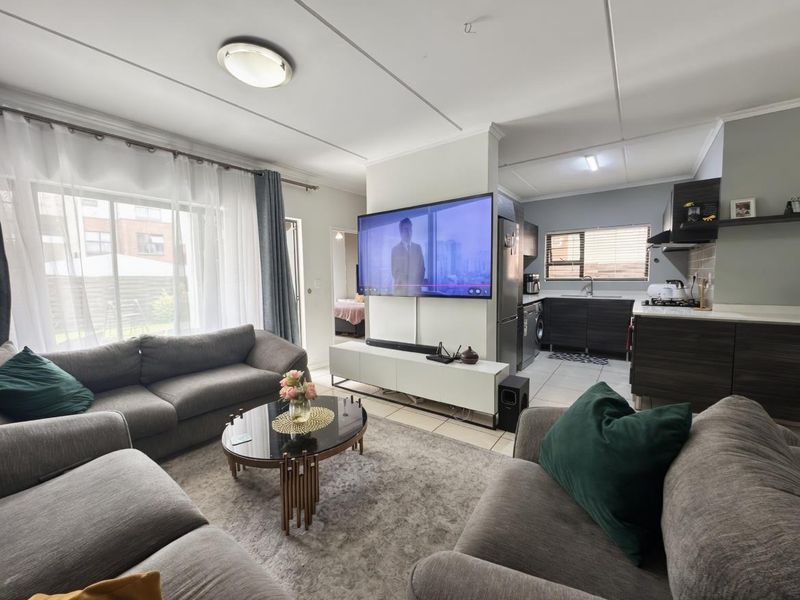 Open-plan living area featuring a modern kitchen with dark cabinetry, tiled floors, and a sliding door leading to an outdoor space.