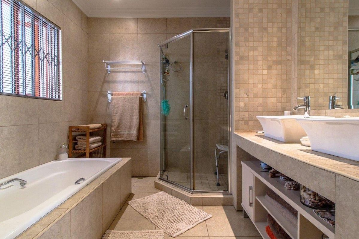 A well-appointed bathroom featuring a built-in bathtub, a separate glass-enclosed shower, and a double vanity with modern vessel sinks.
