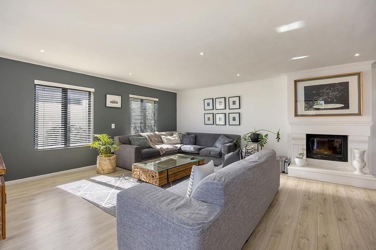 A bright and well-maintained living room featuring a fireplace, modern laminate flooring, and recessed downlights, creating a comfortable and inviting atmosphere.