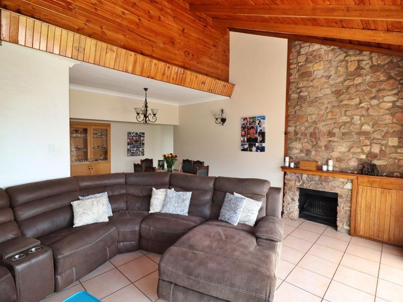 Spacious living room featuring a vaulted timber ceiling, a prominent stone fireplace, and tiled flooring, creating a warm and rustic atmosphere.