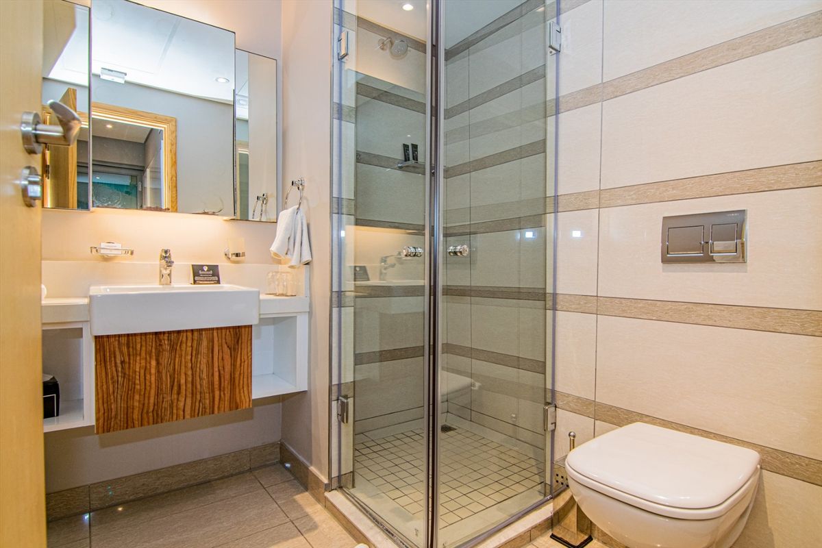Modern bathroom featuring a wall-mounted vanity, glass-enclosed shower, and a wall-hung toilet with integrated flush plate.