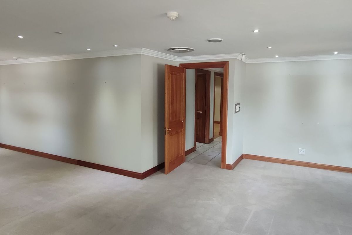 Spacious, empty office area featuring recessed downlighting, timber door frames, and neutral wall finishes, suitable for a professional workspace setup.