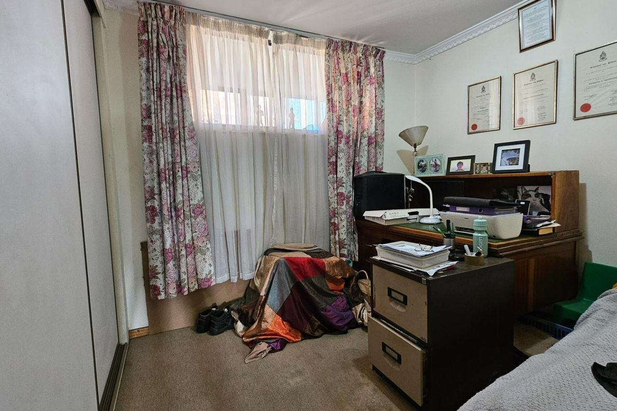 A bedroom featuring built-in sliding door wardrobes, carpeted flooring, and crown molding detail.