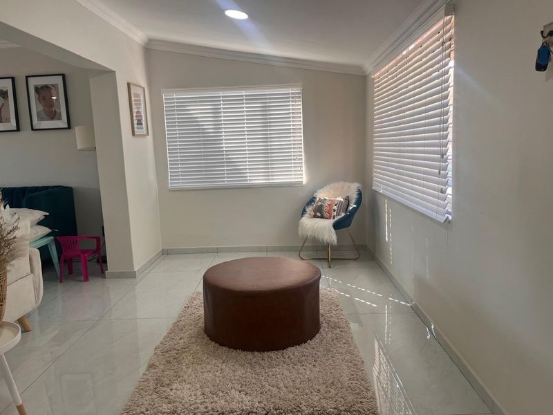A bright living area featuring polished tiled flooring, recessed downlighting, and venetian blinds, offering a clean and neutral foundation for interior design.