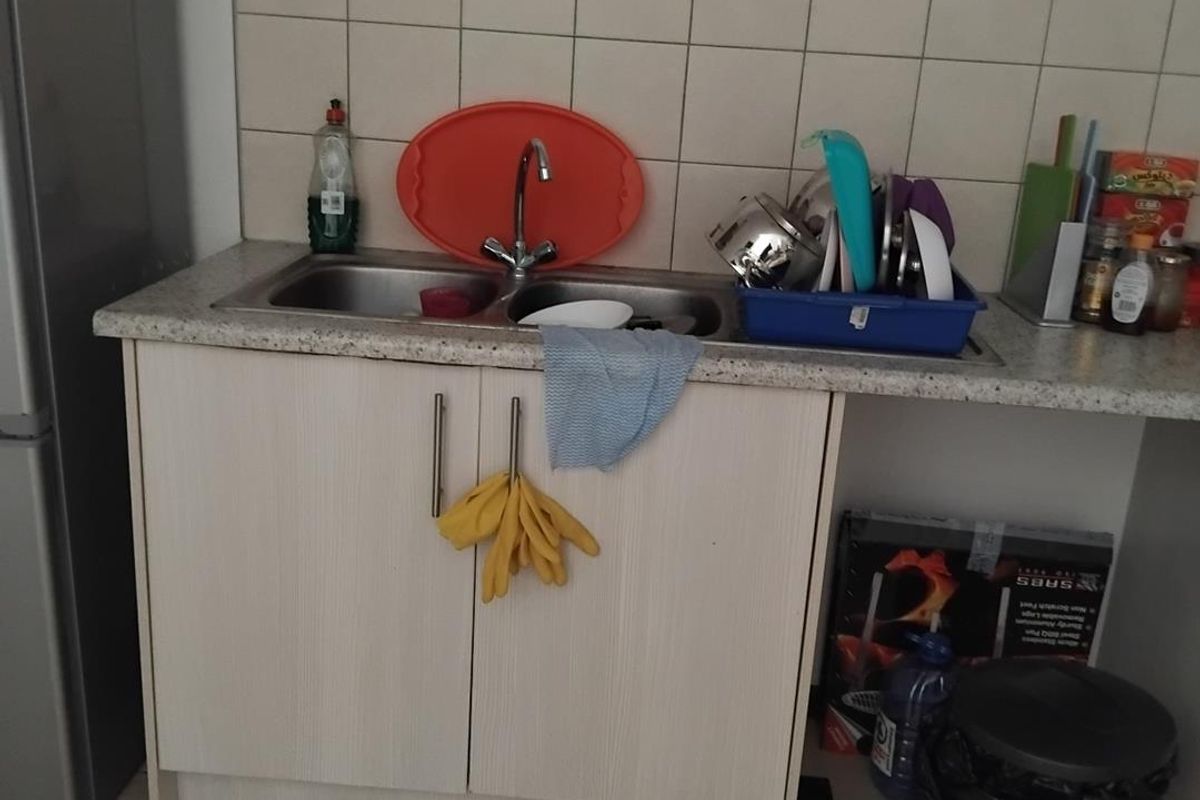A functional kitchen sink area featuring a double basin, laminate countertop, and tiled splashback with under-counter cabinetry.