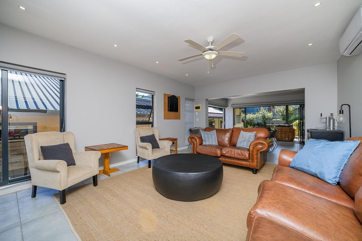 Spacious living area featuring tiled flooring, recessed downlighting, a ceiling fan, and split-system air conditioning, with seamless flow to an outdoor patio.