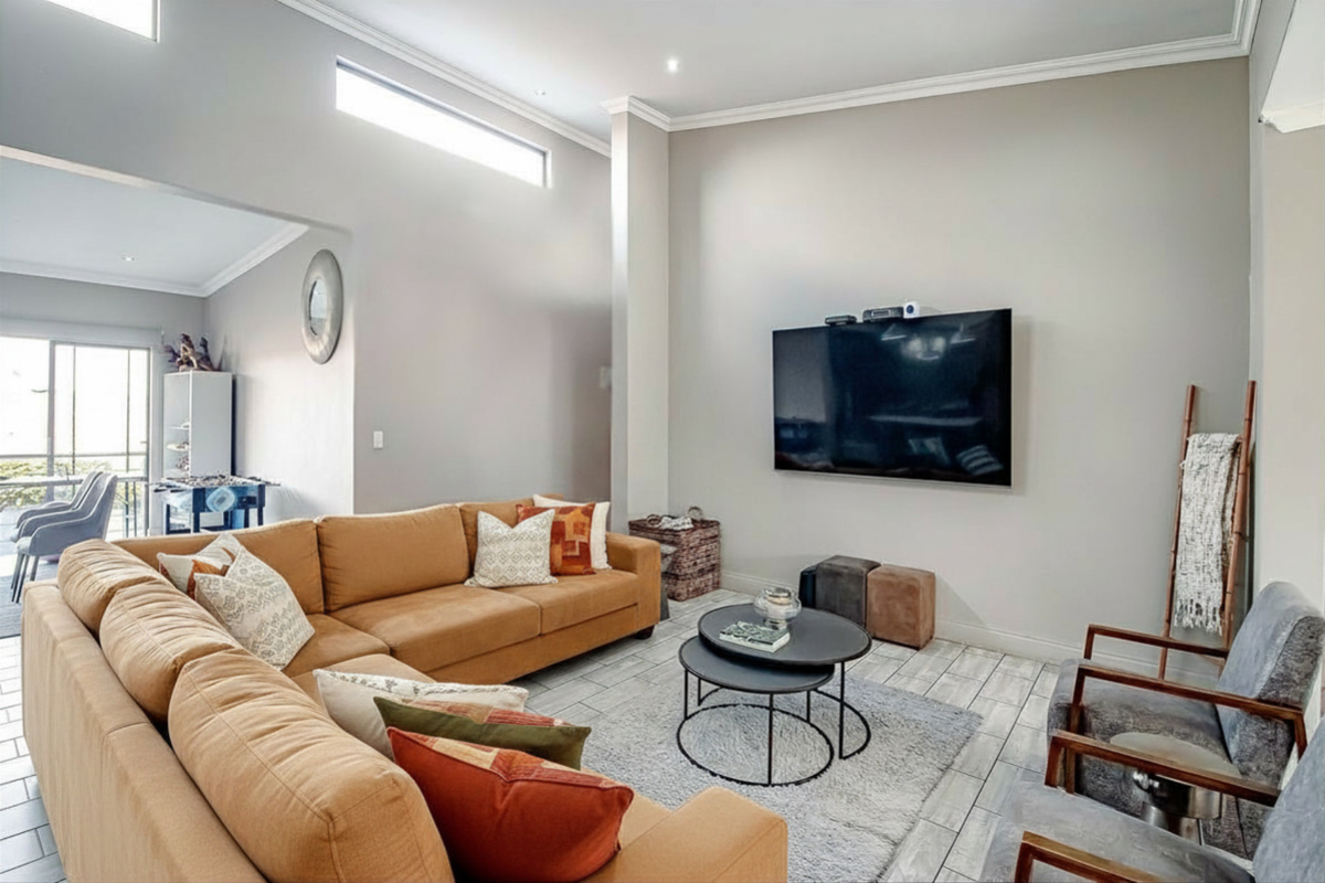 Spacious living room featuring high ceilings with clerestory windows, crown molding, and modern tiled flooring, creating a bright and airy atmosphere.