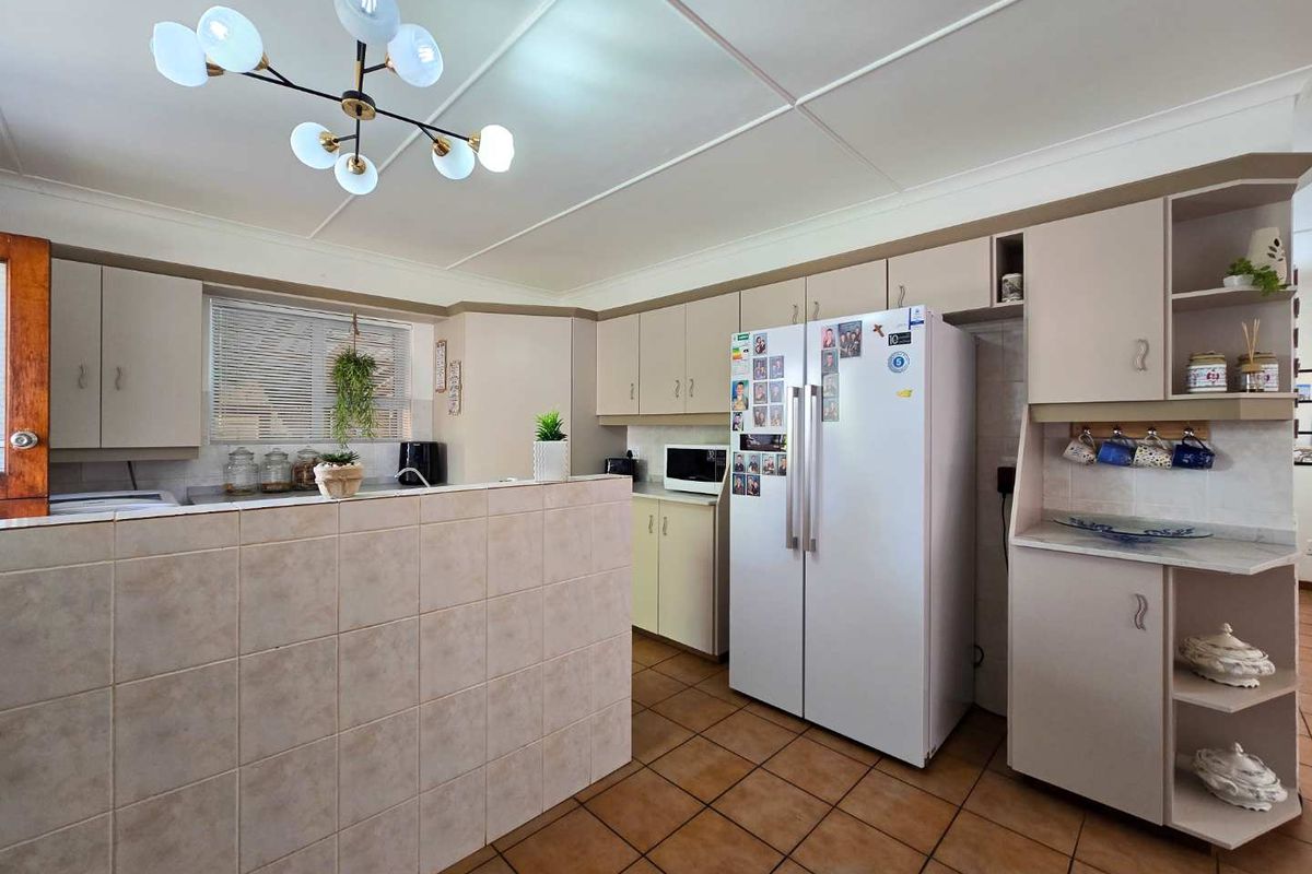 A functional kitchen featuring tiled flooring, a breakfast counter, and ample built-in cabinetry with a neutral finish.