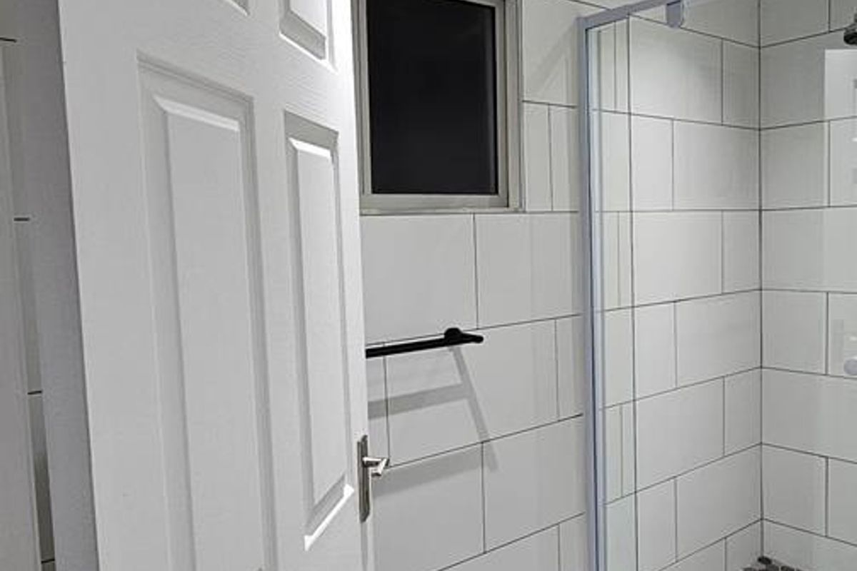 Modern bathroom featuring a glass-enclosed shower with subway wall tiles, mosaic floor tiling, and wood-look flooring.