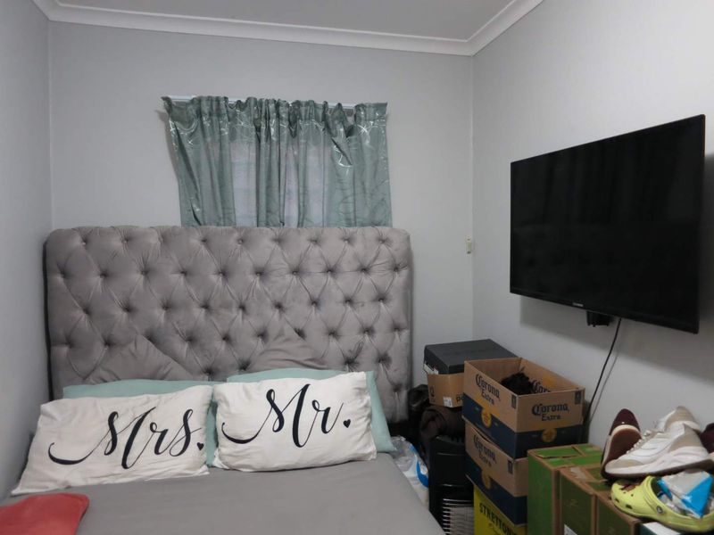 A compact bedroom featuring neutral wall finishes and a wall-mounted television, offering a functional space for rest.