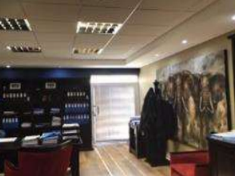 A professional office space featuring built-in shelving, suspended ceilings with recessed lighting, and durable laminate flooring.