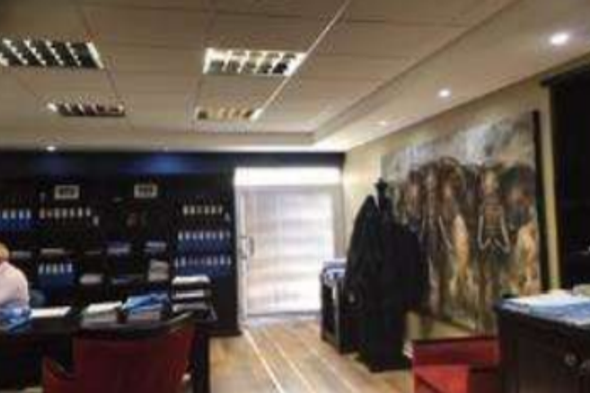 A professional office space featuring built-in shelving, suspended ceilings with recessed lighting, and durable laminate flooring.