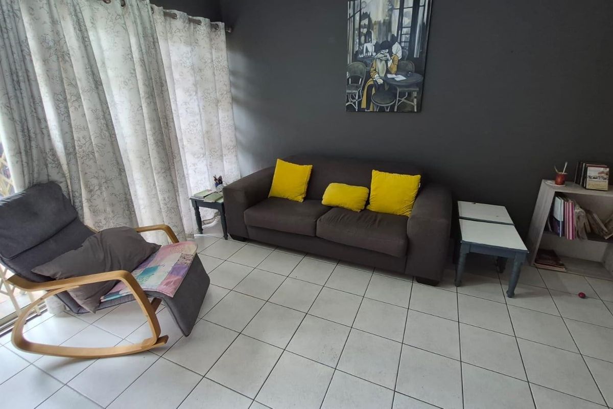 A living room featuring tiled flooring and a sliding glass door with a security gate, providing access to the outdoor area.
