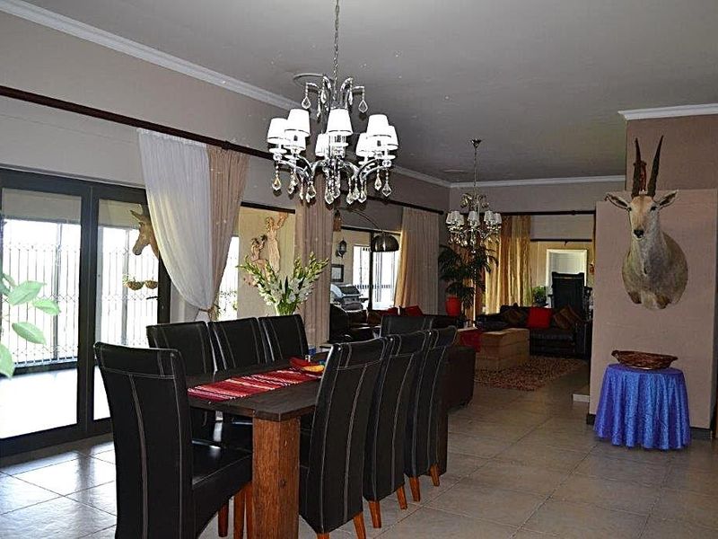 Spacious open-plan living and dining area featuring tiled floors, decorative chandeliers, and large sliding glass doors providing access to the exterior.