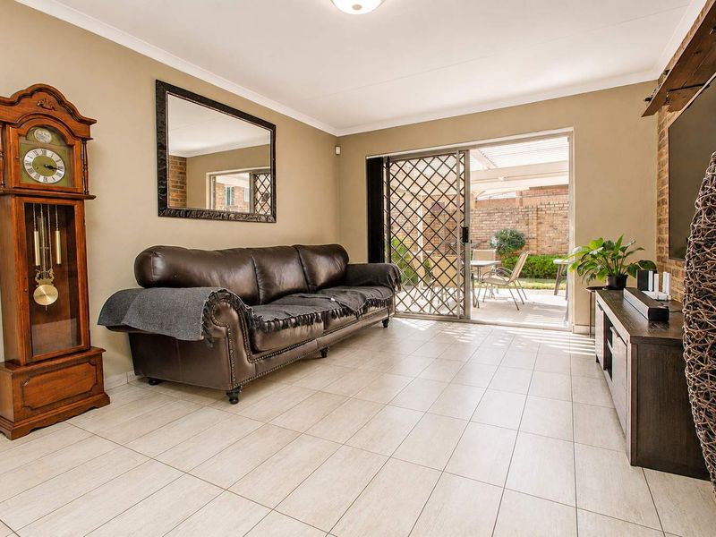 Spacious living room featuring tiled flooring, a brick feature wall, and a sliding glass door providing direct access to the outdoor patio area.