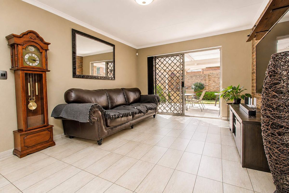 Spacious living room featuring tiled flooring, a brick feature wall, and a sliding glass door providing direct access to the outdoor patio area.