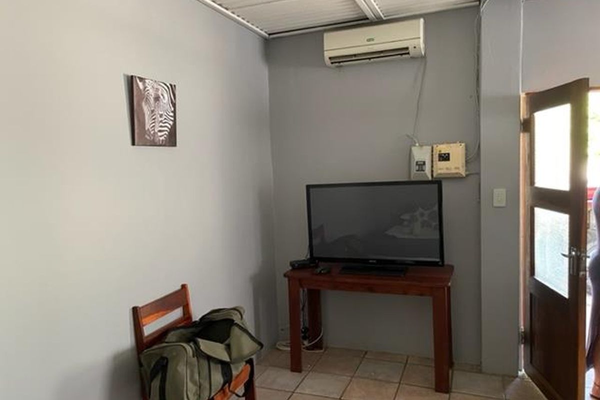 A functional living area featuring tiled flooring, a wall-mounted air conditioning unit, and direct access to an outdoor space.
