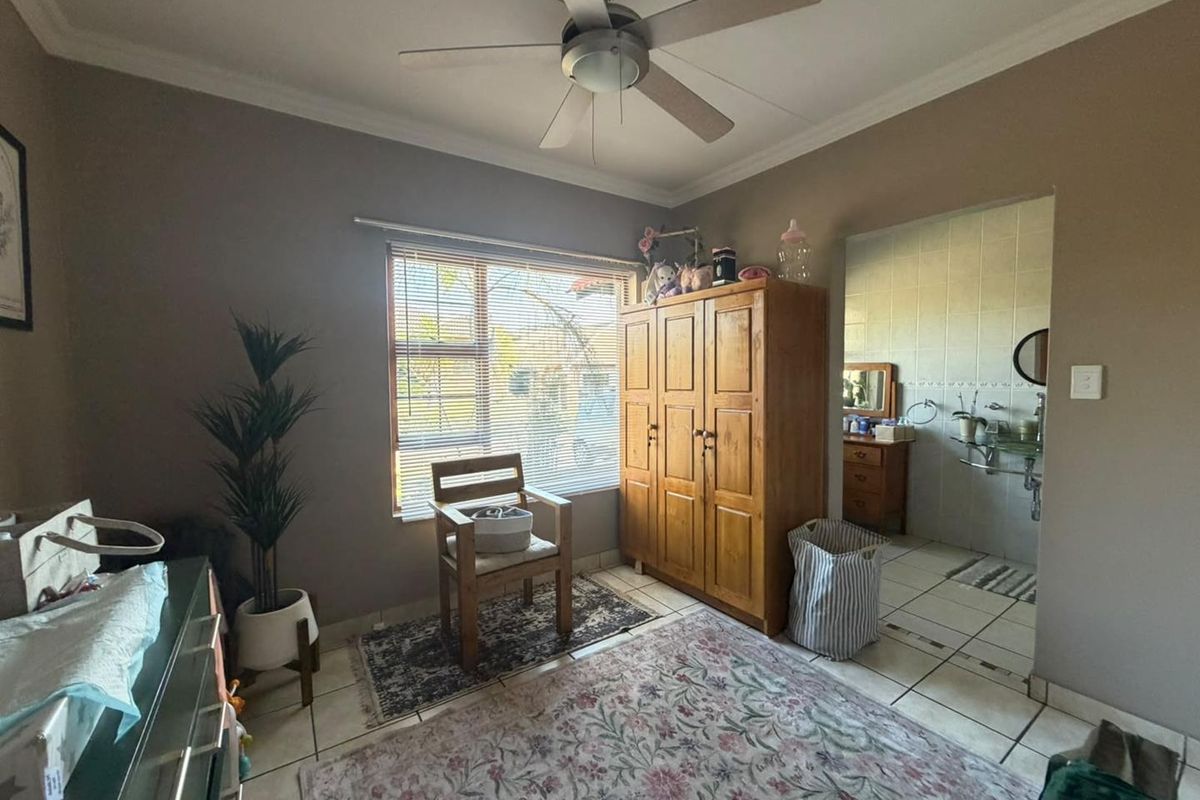 A bedroom featuring tiled flooring, a ceiling fan, and an adjoining en-suite bathroom with tiled walls.