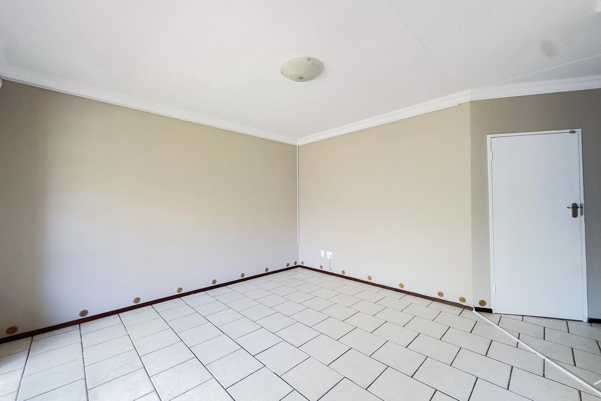 An empty bedroom featuring neutral wall paint, tiled flooring, and a central ceiling light fixture.