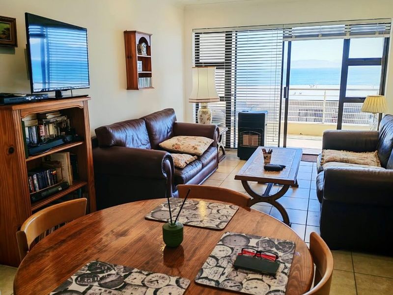 Open plan living and dining area featuring tiled floors and large sliding glass doors leading to a balcony with ocean views.