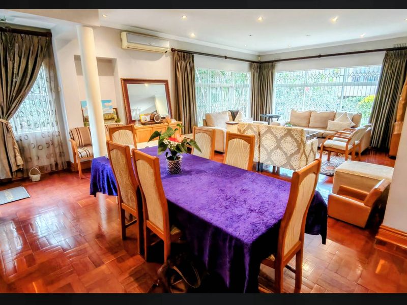 Spacious open-plan living and dining area featuring warm parquet flooring, recessed lighting, and large windows providing ample natural light.