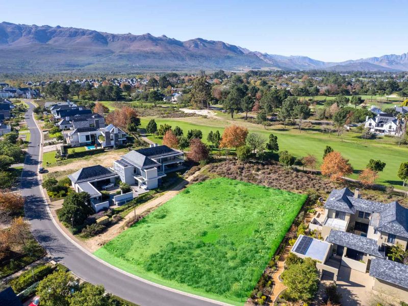 An aerial view of a vacant residential plot situated in a premium estate, featuring direct access to the street and adjacent golf course views.