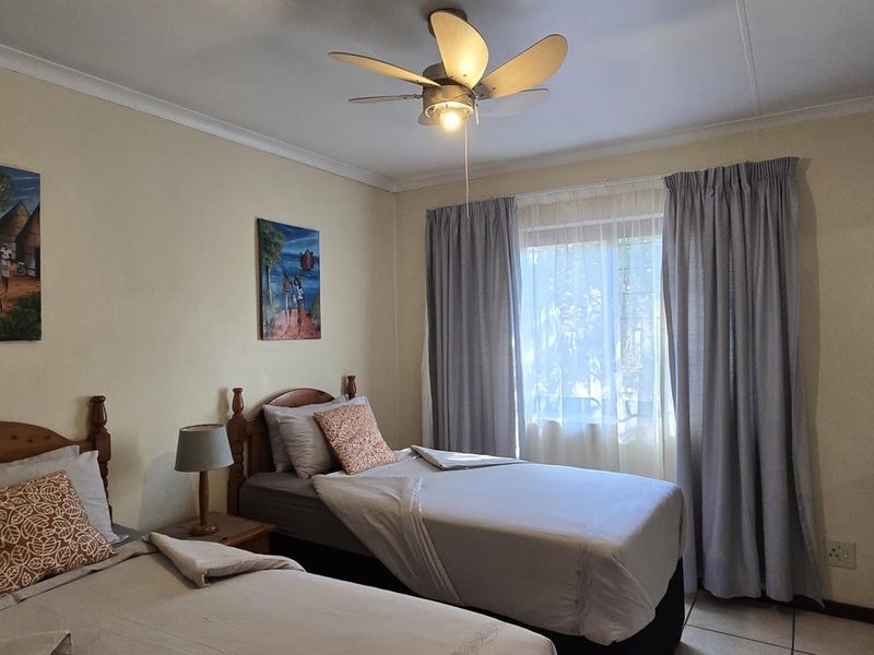 A functional bedroom featuring tiled flooring, a ceiling fan, and built-in storage, offering a comfortable and practical living space.