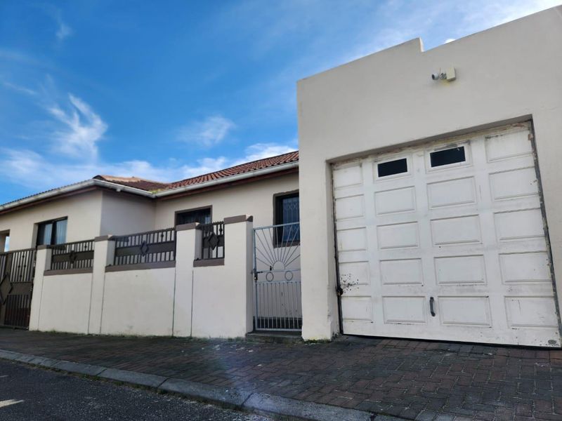Front exterior view of the property featuring a single garage, secure boundary wall with metal gate, and tiled roof.