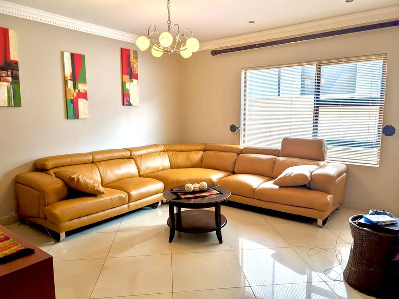 A well-maintained living room featuring polished tiled flooring, decorative crown molding, and recessed lighting, creating a bright and comfortable living space.