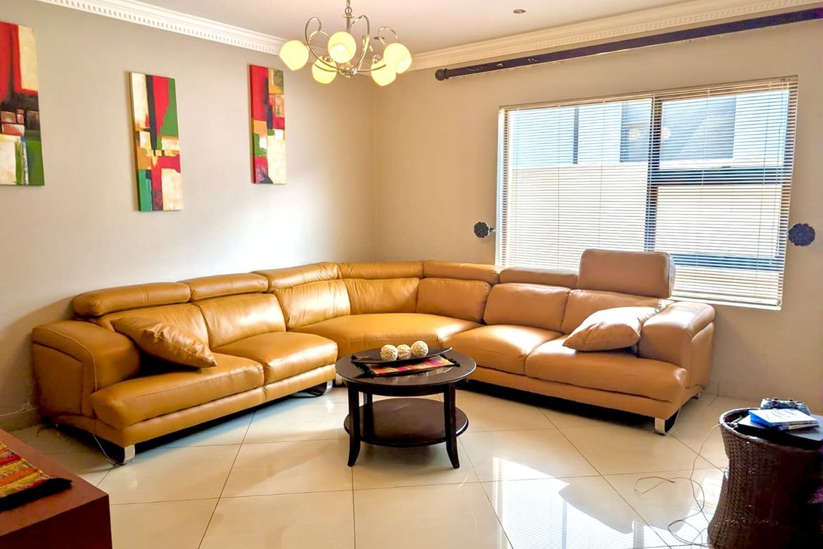 A well-maintained living room featuring polished tiled flooring, decorative crown molding, and recessed lighting, creating a bright and comfortable living space.