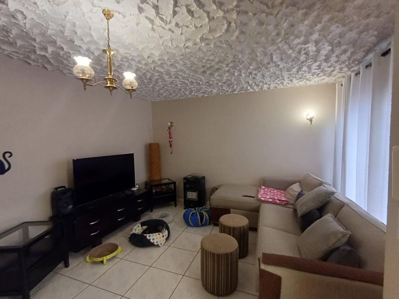 A living room featuring tiled flooring, a textured ceiling, and traditional lighting fixtures, offering a functional space ready for modern updates.