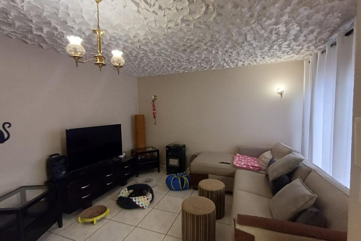 A living room featuring tiled flooring, a textured ceiling, and traditional lighting fixtures, offering a functional space ready for modern updates.