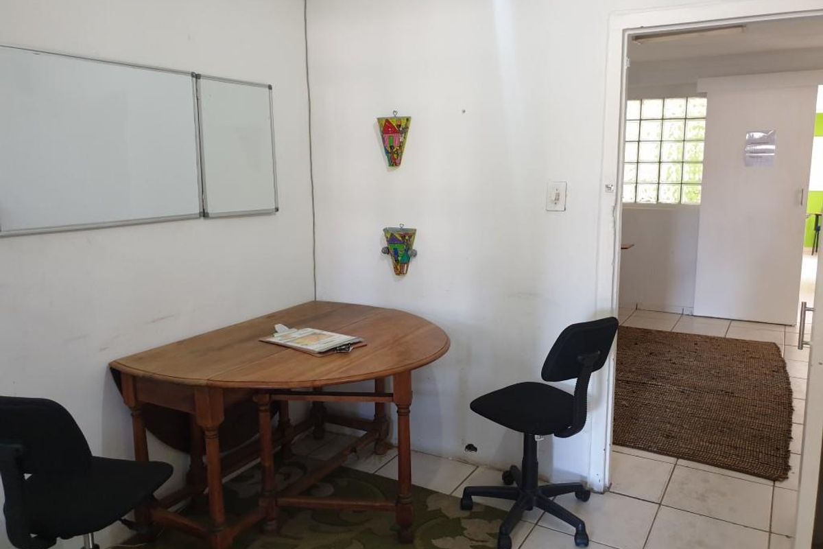 A functional office space featuring tiled flooring, a wall-mounted whiteboard, and a doorway leading to an adjacent room with glass block windows.