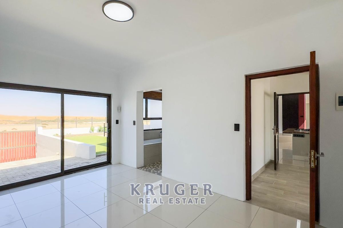 Bright living area featuring large sliding glass doors with outdoor views, tiled flooring, and direct access to adjacent rooms.