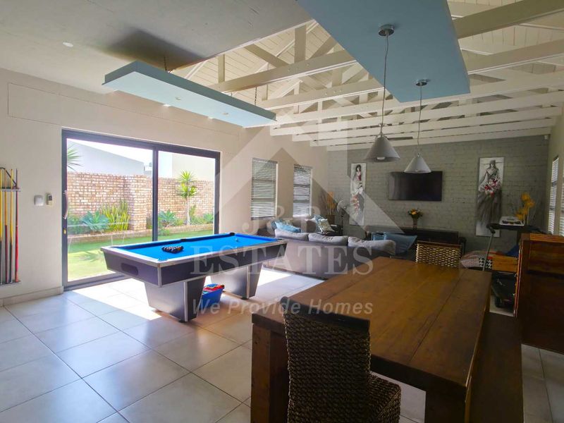 Spacious open-plan living area featuring exposed timber beam ceilings, tiled flooring, and large sliding glass doors providing seamless access to the rear garden.