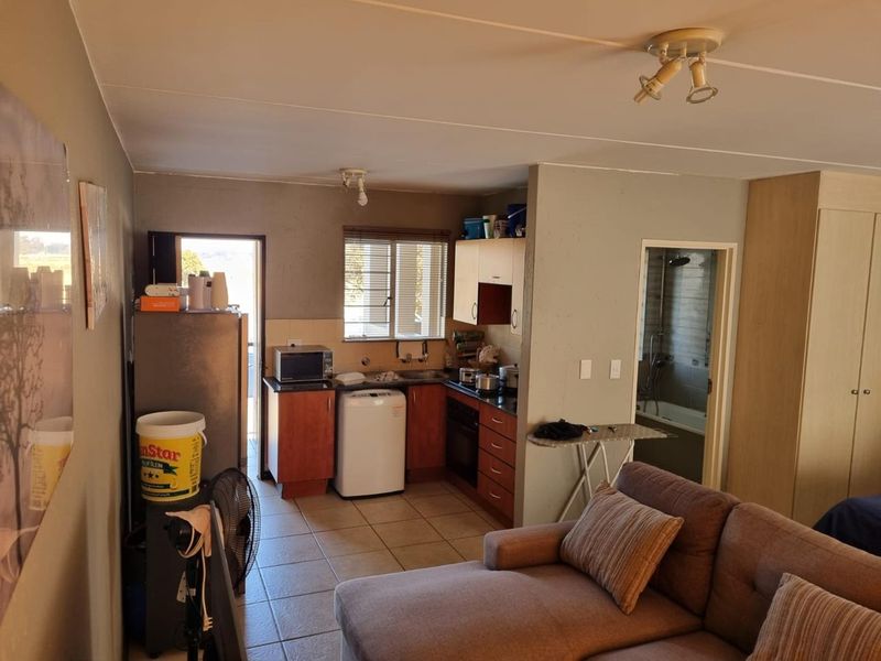 Open-plan living area featuring a compact kitchen with built-in cabinetry, tiled flooring, and direct access to an adjacent bathroom.