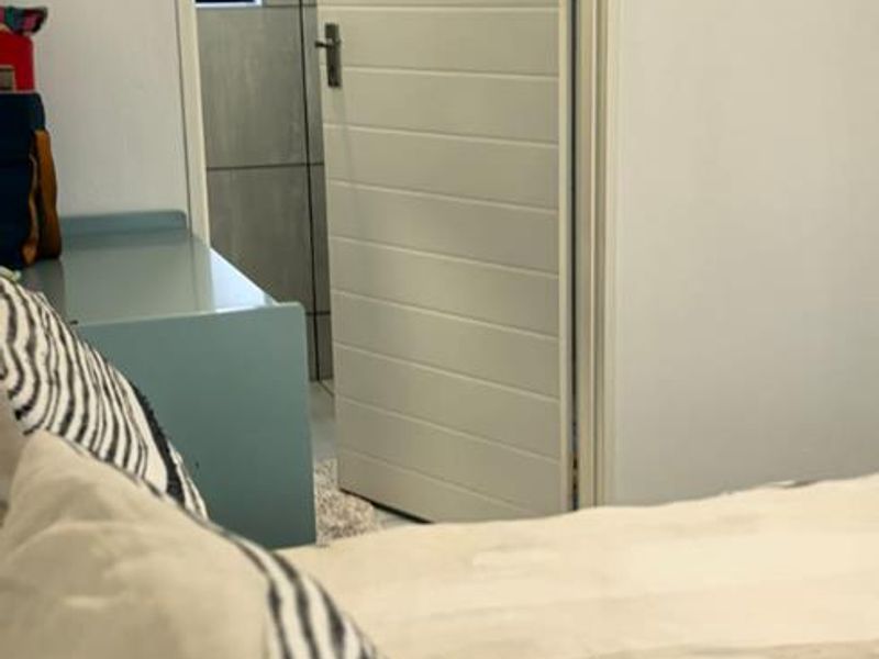 A view from a bedroom looking through an open doorway into an adjacent tiled bathroom.