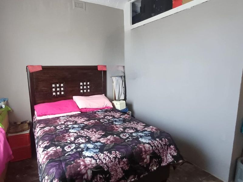 A bedroom featuring tiled flooring, a decorative pressed metal ceiling, and a built-in overhead storage compartment above the wall.