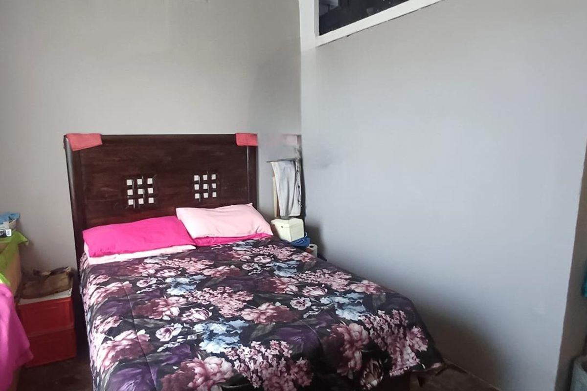 A bedroom featuring tiled flooring, a decorative pressed metal ceiling, and a built-in overhead storage compartment above the wall.