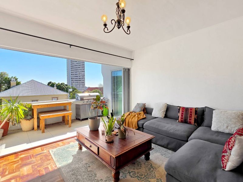 Open plan living area featuring parquet flooring and large sliding glass doors that open onto a private balcony.