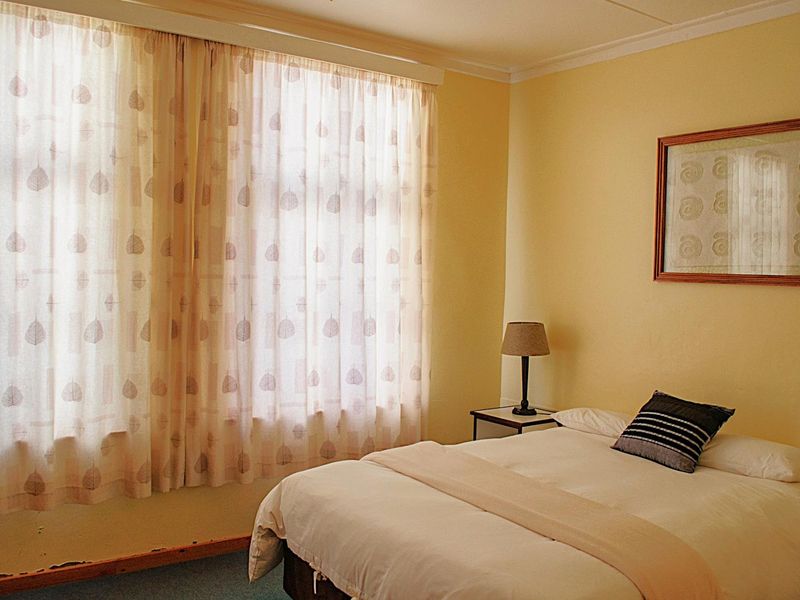 A bedroom featuring yellow walls, coving, and skirting boards, with visible wear to the baseboards.