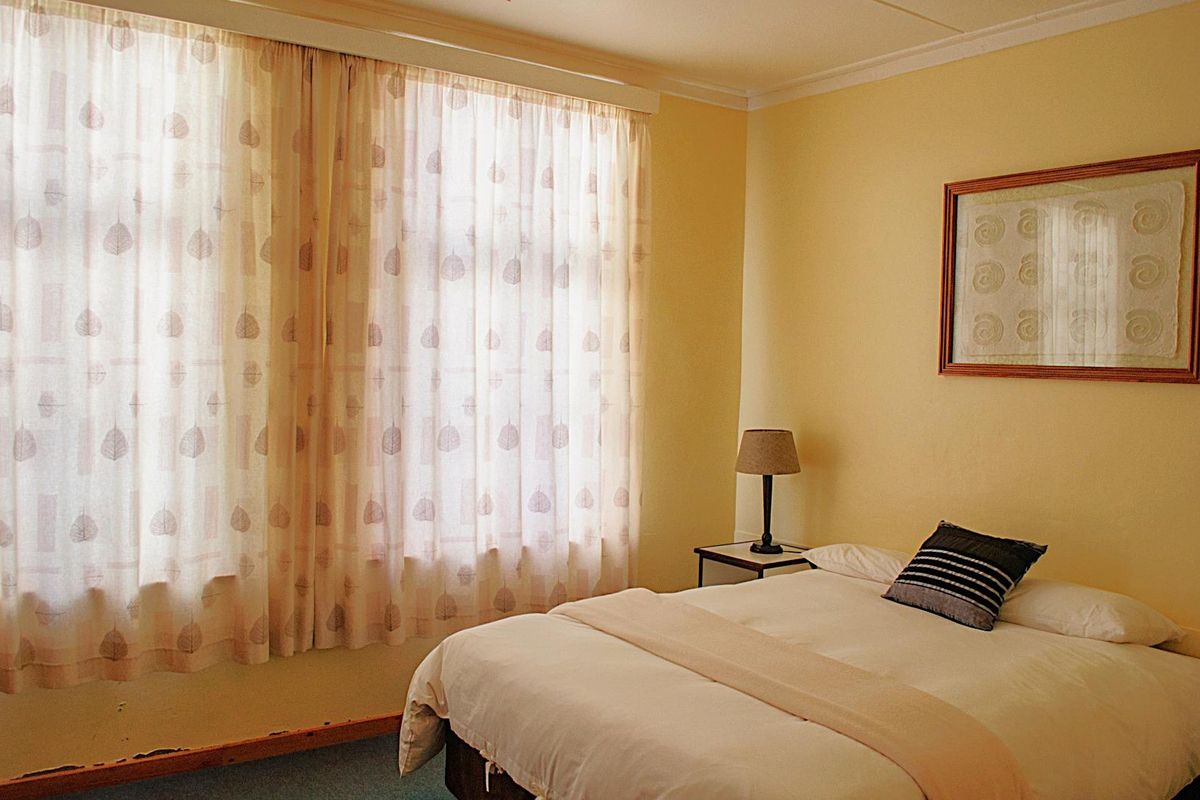 A bedroom featuring yellow walls, coving, and skirting boards, with visible wear to the baseboards.