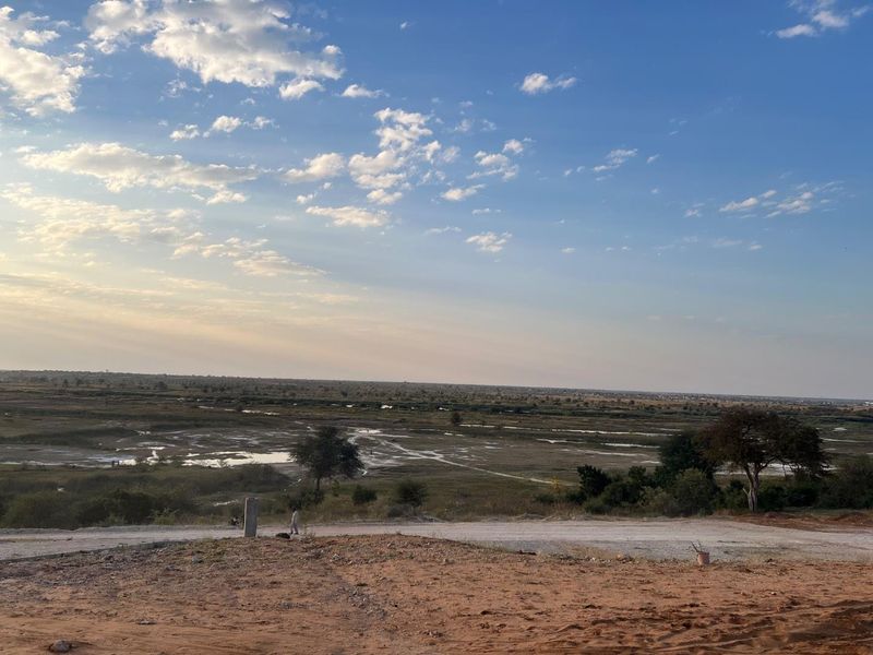 A wide-angle view of an expansive, undeveloped residential land plot featuring natural terrain and distant landscape vistas.