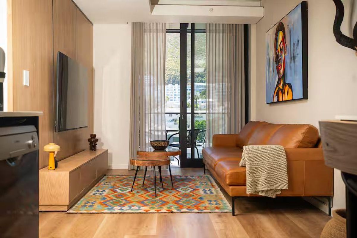 Modern living room featuring light wood flooring, built-in cabinetry, and large glass doors leading to a private balcony with mountain views.