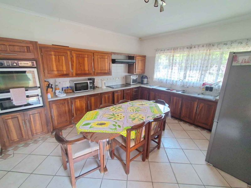 Spacious kitchen featuring extensive wooden cabinetry, built-in oven, extractor fan, double sink, and tiled flooring, offering a functional layout with ample storage space.