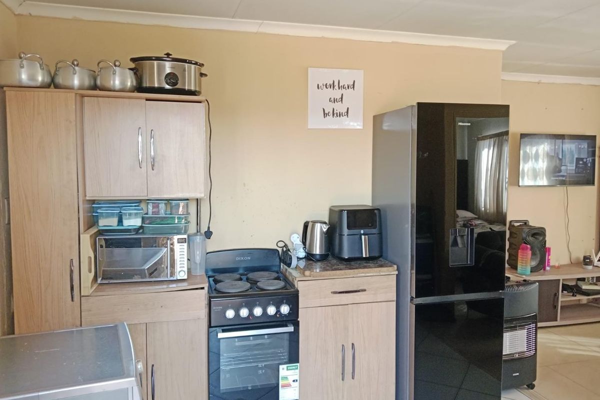 A functional kitchen area featuring light wood-finish cabinetry, a freestanding stove with oven, and tiled flooring, providing essential cooking and storage space.