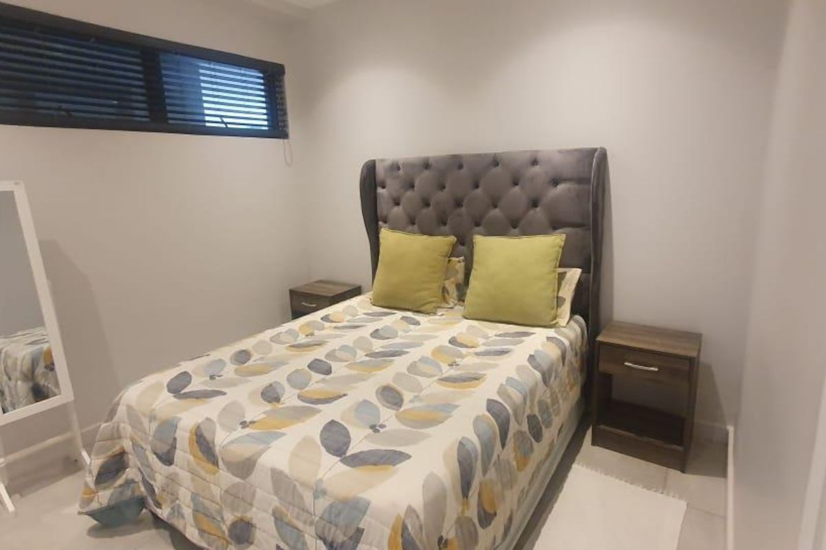 A compact bedroom featuring neutral wall finishes, tiled flooring, and a high-set horizontal window providing natural light.